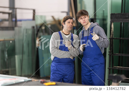 Adult and young man discussing work in glass factory Adult and young man discussing work in glass factory 138412782