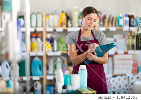 store employee conducts an inventory and writes on paper store employee conducts an inventory and writes on paper 138412855