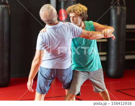 Middle aged man practicing close combat wrestling Middle aged man practicing close combat wrestling 138412916