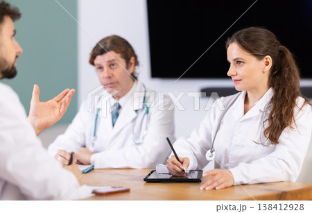 Medical professionals discussing topic during clinical meeting at table Medical professionals discussing topic during clinical meeting at table 138412928