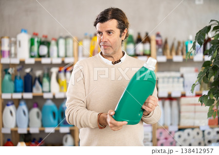Adult man buyer chooses detergent in store Adult man buyer chooses detergent in store 138412957