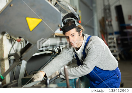 Adult man puts steel part on machine Adult man puts steel part on machine 138412960