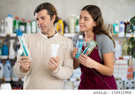 Female salesperson helps man choose best toothbrush and dental kit Female salesperson helps man choose best toothbrush and dental kit 138412966