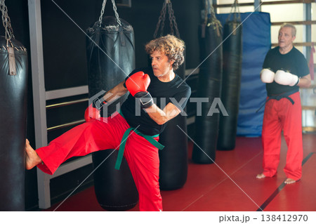 Man practicing kicks with punchbag during Krav Maga workout Man practicing kicks with punchbag during Krav Maga workout 138412970