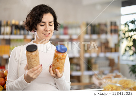 Adult woman chooses beans at grocery store Adult woman chooses beans at grocery store 138413022