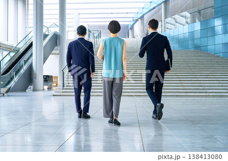 未来へ向かってオフィスビルを歩くビジネスチームの後ろ姿 138413080