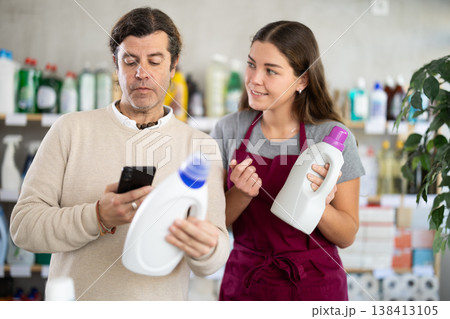 Customer scanning detergent barcode while saleswoman offering alternative Customer scanning detergent barcode while saleswoman offering alternative 138413105