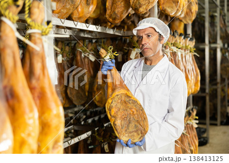 Man employee checks jamon. Quality control Man employee checks jamon. Quality control 138413125