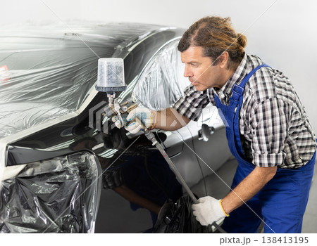 Experienced auto painter working in car repair workshop 138413195