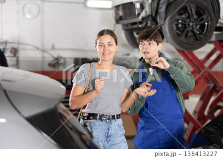 Mechanic guy giving car keys to woman client Mechanic guy giving car keys to woman client 138413227