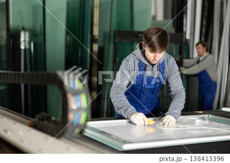 In workshop for production of glass products, guy co-worker cuts off excess from workpiece 138413396