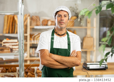 Portrait of friendly baker selling fresh baguettes and croissants in bakery 138413452