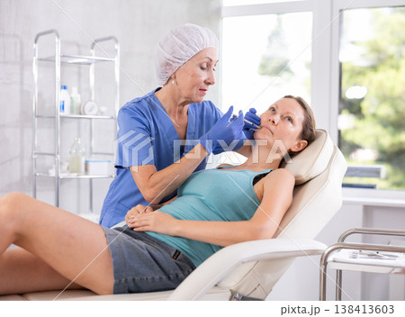 Woman getting procedure of injection contouring and for facial correction in clinic 138413603