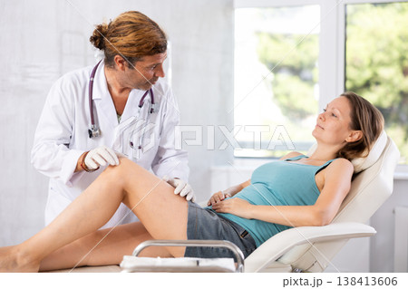 Doctor in medical gloves exam woman's legs. Doctor in medical gloves exam woman's legs. 138413606