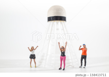 Miniature figures cheering near oversized shuttlecock sculpture 138413711