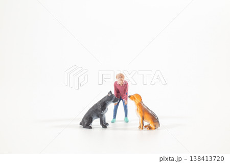 Miniature figure interacting with two seated dogs Miniature figure interacting with two seated dogs 138413720