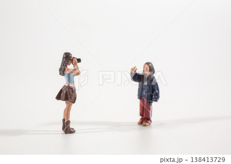 Miniature photographer aiming camera toward standing figure Miniature photographer aiming camera toward standing figure 138413729
