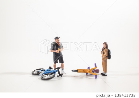 a Miniature cyclists standing near fallen bicycles a Miniature cyclists standing near fallen bicycles 138413738