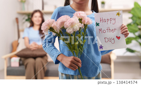 Daughter presenting flowers and card for Mother's Day Daughter presenting flowers and card for Mother's Day 138414574