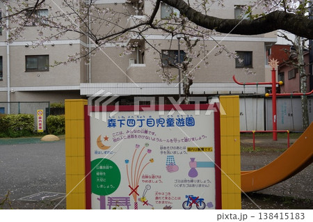 桜咲く春の「森下四丁目児童遊園」。公園の利用ルールを記した案内看板と遊具の風景 桜咲く春の「森下四丁目児童遊園」。公園の利用ルールを記した案内看板と遊具の風景 138415183