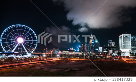 Vibrant night Hong Kong city skyline featuring an illuminated Ferris wheel 138417329