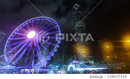 A vibrant urban night scene featuring a glowing Ferris wheel. Hong Kong 138417334