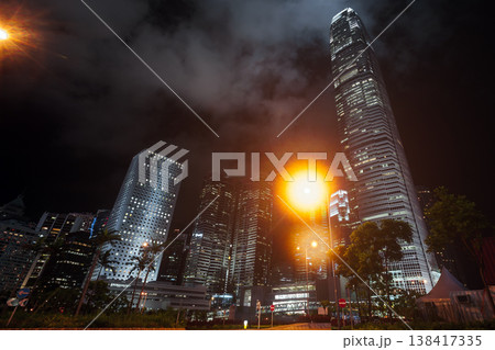 A dramatic nighttime cityscape featuring towering illuminated skyscrapers 138417335