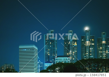 Bangkok skyline with illuminated residential towers and moon at night, Modern cityscape with highrise buildings and glowing windows under night sky Bangkok skyline with illuminated residential towers and moon at night, Modern cityscape with highrise buildings and glowing windows under night sky 138417851