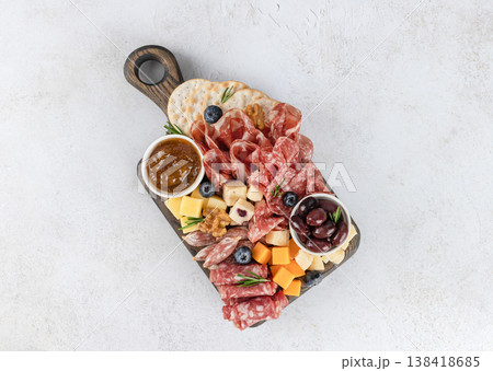 Charcuterie board with sliced salami, cheeses, olives, fig jam, crackers, walnuts on white background. Top view. 138418685
