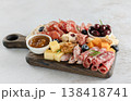 Close-up of charcuterie board with salami, cheeses, olives, jam, nuts and blueberries on rustic wooden board.  138418741