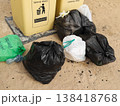 Garbage bags left beside waste bins in a protected natural zone, reflecting poor waste management. 138418768