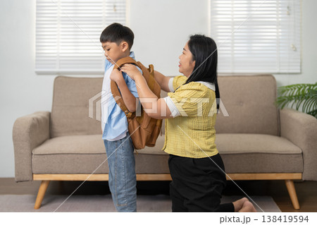 Mother preparing her son for school with a backpack 138419594