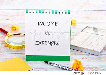 Notepad: INCOME VS EXPENSES, plus calculator, magnifier, pen on wood. For fiscal analysis Notepad: INCOME VS EXPENSES, plus calculator, magnifier, pen on wood. For fiscal analysis 138419725