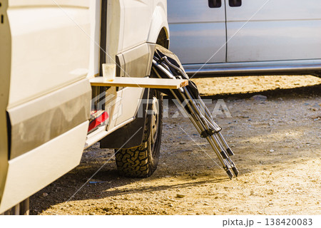 Van with picnic folding external table, and chair ready for outdoor living during daytime at a campsite 138420083