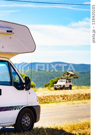 Camping setup in a green field with vehicles and a rooftop tent during daylight hours Camping setup in a green field with vehicles and a rooftop tent during daylight hours 138420105
