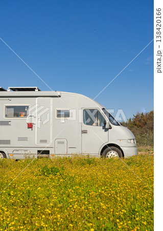 Camping car rv parked close to spring meadow with yellow flowers with blue sky during daytime 138420166