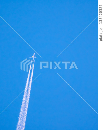 Airplane flying high in the sky leaving white trails during clear day with blue background Airplane flying high in the sky leaving white trails during clear day with blue background 138420522