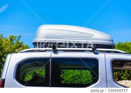 Silver roof box on a vehicle parked under blue sky. Travel, family vacation. Accessories for transportation. Silver roof box on a vehicle parked under blue sky. Travel, family vacation. Accessories for transportation. 138420557