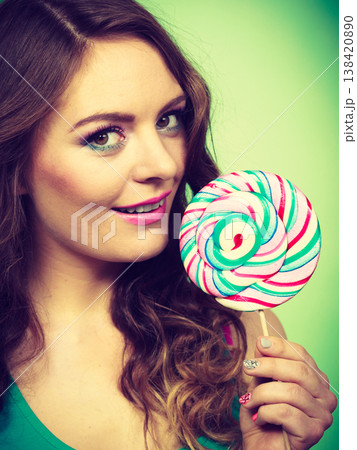 Smiling girl with lollipop candy on green 138420890