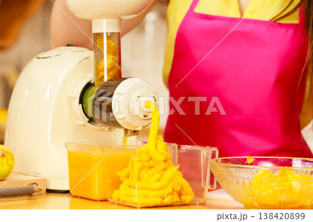 Woman making orange juice in juicer machine 138420899