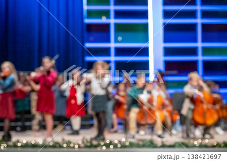 Defocused middle school orchestra band on stage for a concert. 138421697