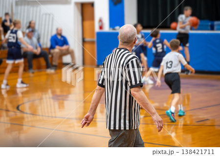 Boys basketball game in gym with referee calling the plays during a weekend match in the afternoon Boys basketball game in gym with referee calling the plays during a weekend match in the afternoon 138421711