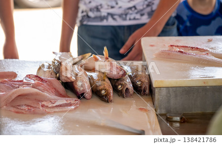 Fresh fish being prepared at a local market in the afternoon sun, showcasing local culinary traditions and craftsmanship Fresh fish being prepared at a local market in the afternoon sun, showcasing local culinary traditions and craftsmanship 138421786