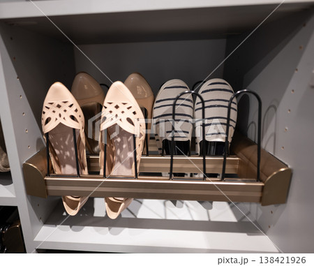 Stylish shoes arranged on a storage shelf in a closet for easy access and organization during the day 138421926