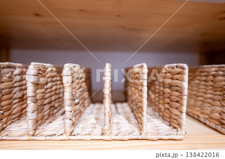 Woven storage baskets arranged on a wooden shelf in a home storage area during daylight hours 138422016