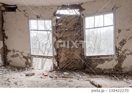 Dilapidated Abandoned Room With Cracked Walls, Broken Windows And Exposed Lath Structure Showing Decay In Winter Forest View 138422270
