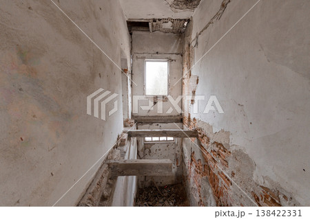 Dilapidated Interior Stairwell With Exposed Brick Walls And Broken Plaster Showing Signs Of Decay In Abandoned Building With Natural Light From Window Dilapidated Interior Stairwell With Exposed Brick Walls And Broken Plaster Showing Signs Of Decay In Abandoned Building With Natural Light From Window 138422331