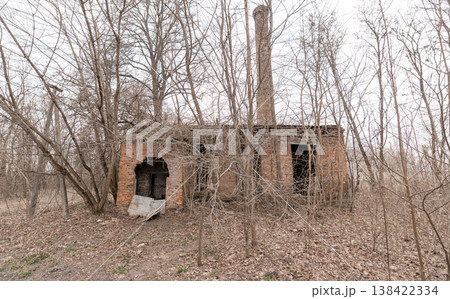 Abandoned Brick Factory Ruin With Tall Chimney Standing In Overgrown Winter Woods Showing Decay And Nature Reclaiming Industrial Site Amidst Bare Trees Abandoned Brick Factory Ruin With Tall Chimney Standing In Overgrown Winter Woods Showing Decay And Nature Reclaiming Industrial Site Amidst Bare Trees 138422334