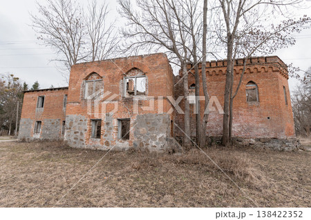 Abandoned Red Brick Ruin With Gothic Arched Windows Standing In Overgrown Field Under Grey Sky Showing Weathered Stone Foundation And Bare Trees Abandoned Red Brick Ruin With Gothic Arched Windows Standing In Overgrown Field Under Grey Sky Showing Weathered Stone Foundation And Bare Trees 138422352