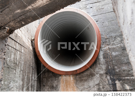 Close-Up View Of A Large Industrial Corrugated Pipe With White Interior And Orange Rim Set Against Weathered Concrete Walls In An Underground Utility Tunnel Environment Close-Up View Of A Large Industrial Corrugated Pipe With White Interior And Orange Rim Set Against Weathered Concrete Walls In An Underground Utility Tunnel Environment 138422373